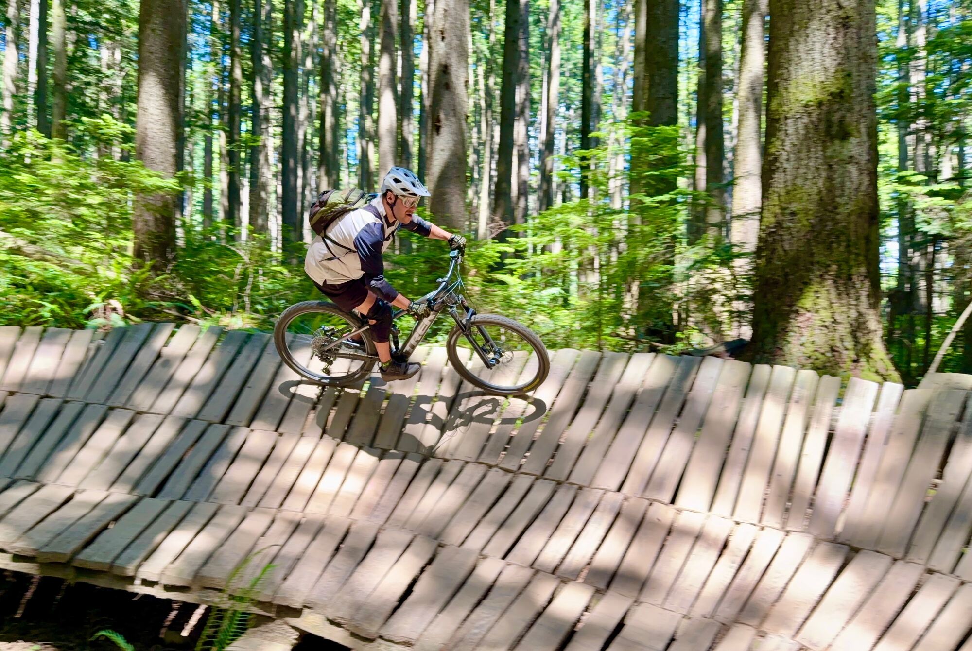 Rider railing a wooden berm through the forest
