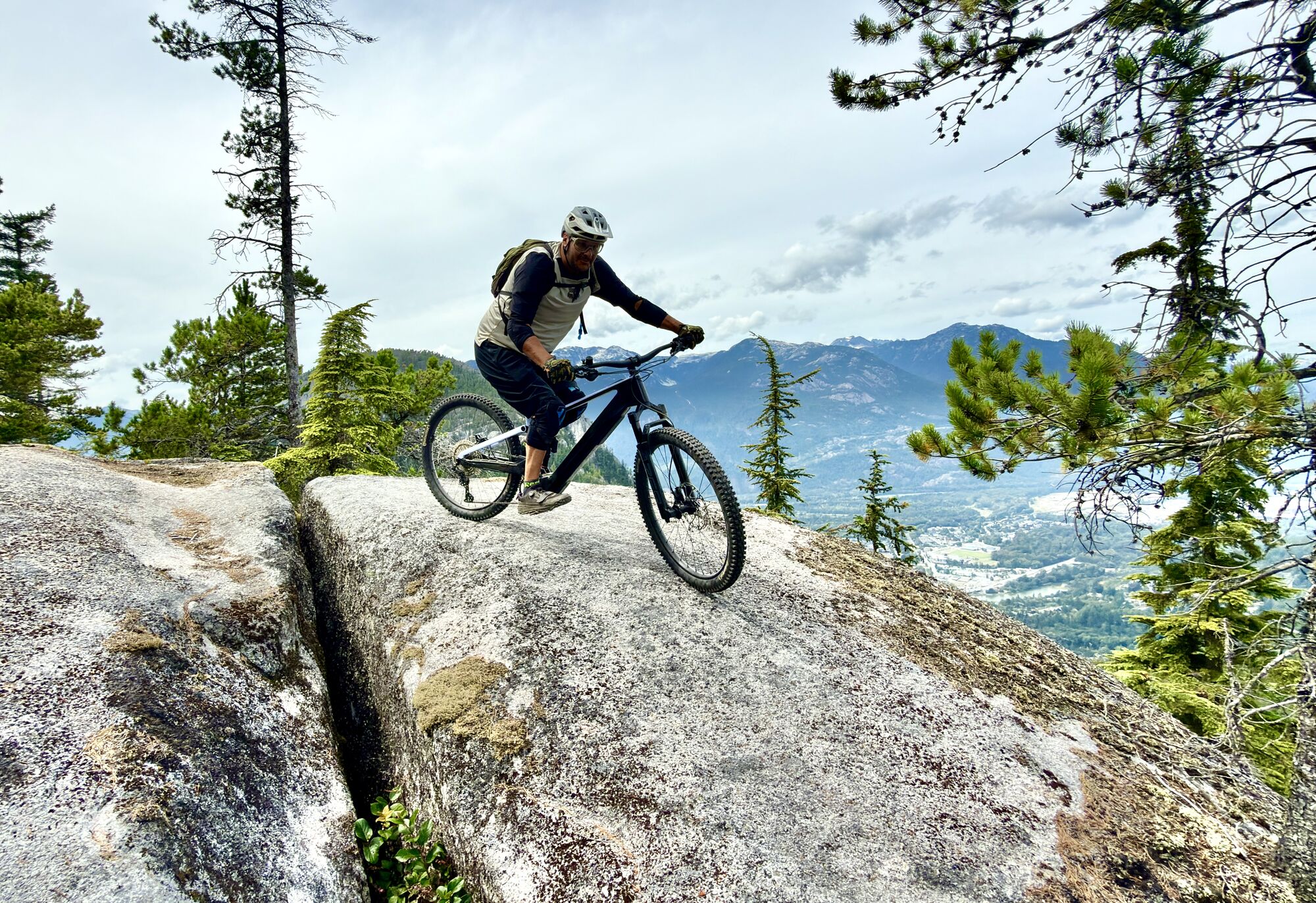 Rider cresting a granite slab above the Squamish valley