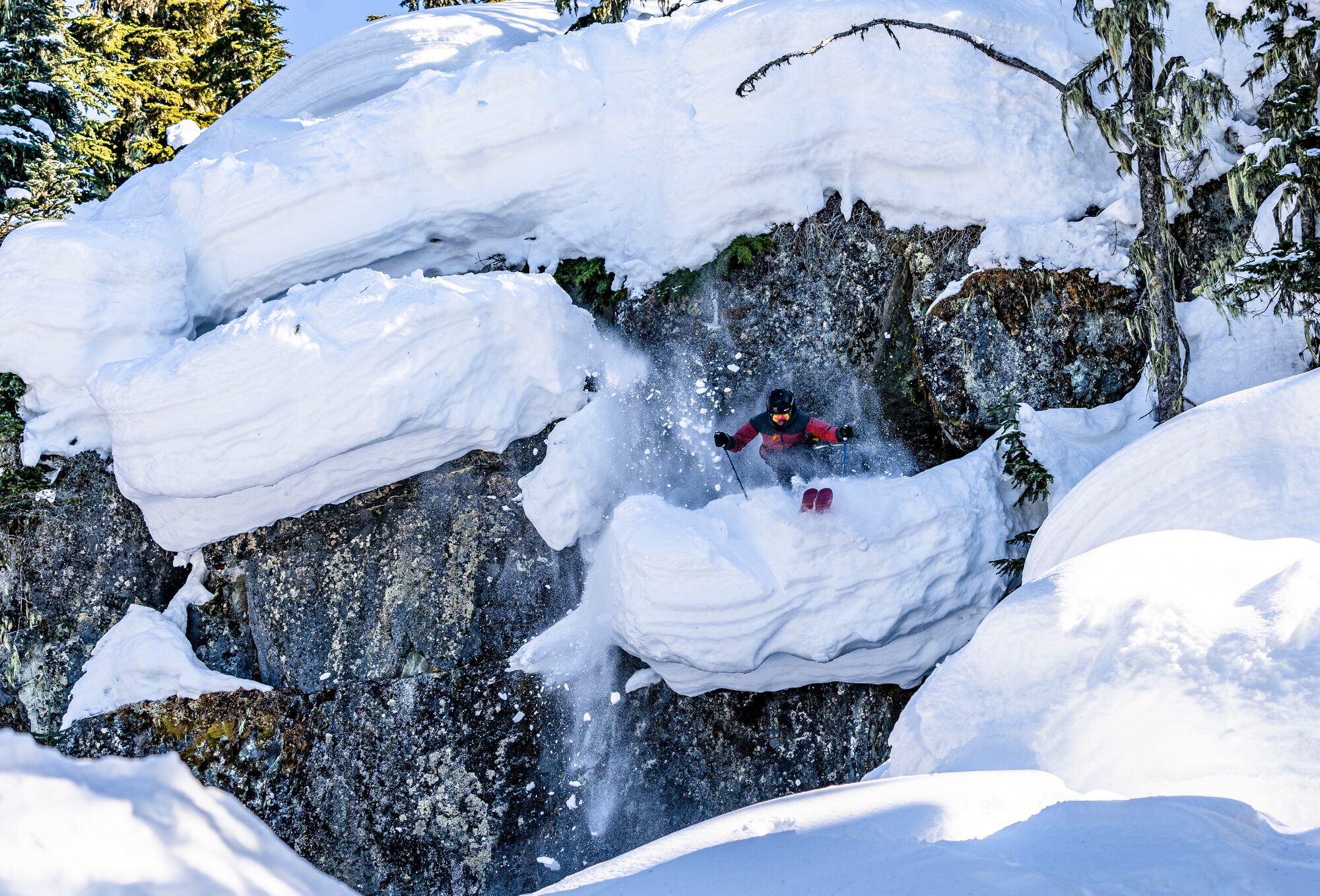 Skier dropping through a snow-filled rock chute