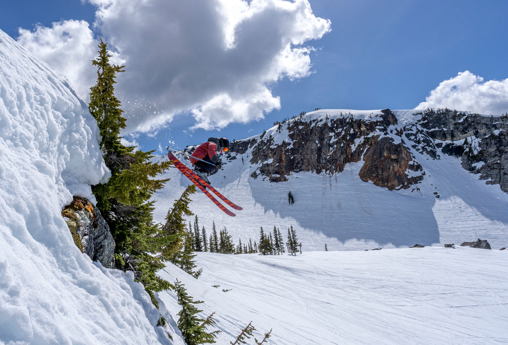 Skier catching air off a cliff band under bluebird skies